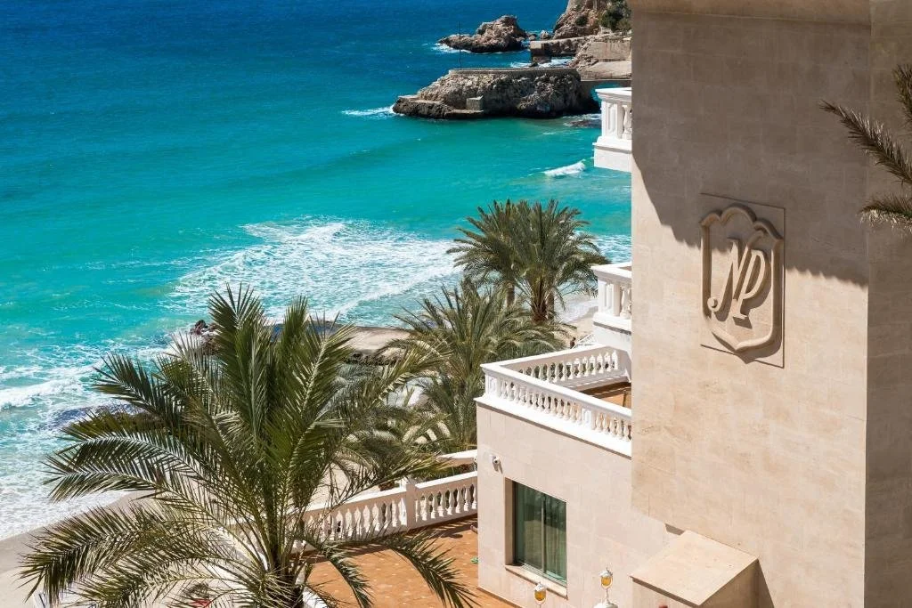 Nixe Palace Mallorca hotel facade above turquoise sea and palm trees at Cala Major beach