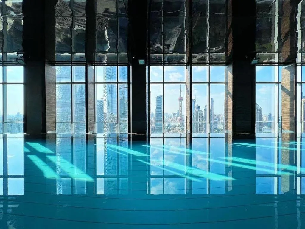 Regent Shanghai Pudong indoor infinity pool with mirrored ceiling reflecting the Pudong skyline and Oriental Pearl Tower through floor-to-ceiling windows