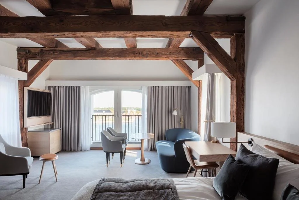 Admiral Hotel Copenhagen hotel room with original warehouse timber beams and harbor view through arched window and balcony