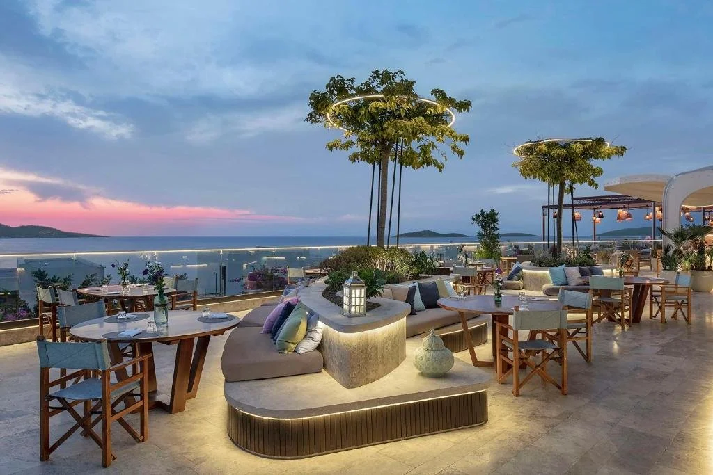 Susona Bodrum LXR Hotels open-air terrace restaurant at sunset with illuminated tree canopies and Aegean Sea view
