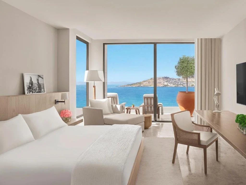 The Bodrum EDITION sea-view room with floor-to-ceiling sliding glass door and terrace overlooking Aegean Sea and coastal headland