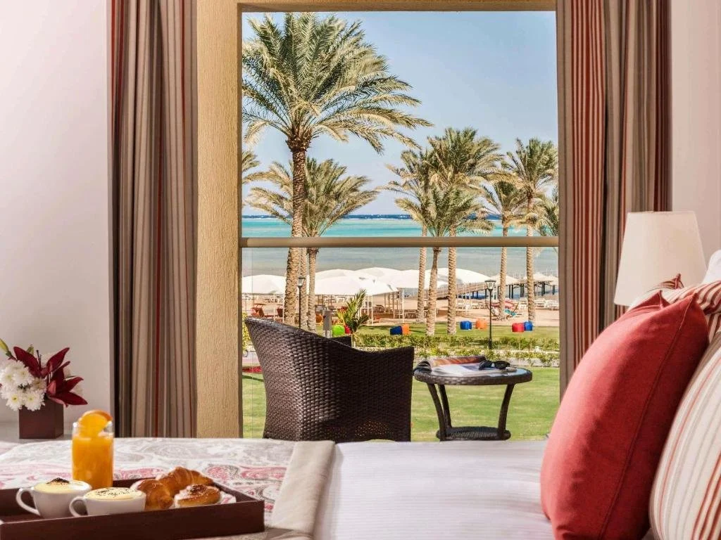 Rixos Premium Seagate Sharm El Sheikh room window framing palm trees, beach umbrellas, and the Red Sea