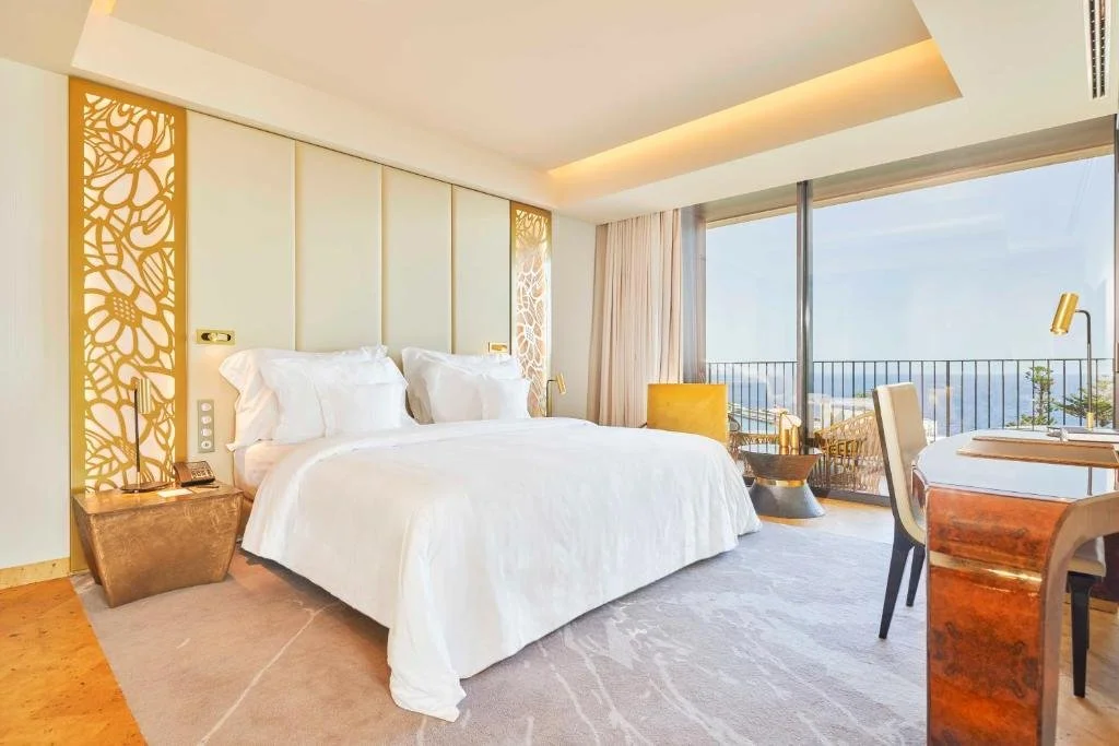 Savoy Palace Funchal sea-view room with carved gold floral headboard panels and balcony over the Atlantic Ocean