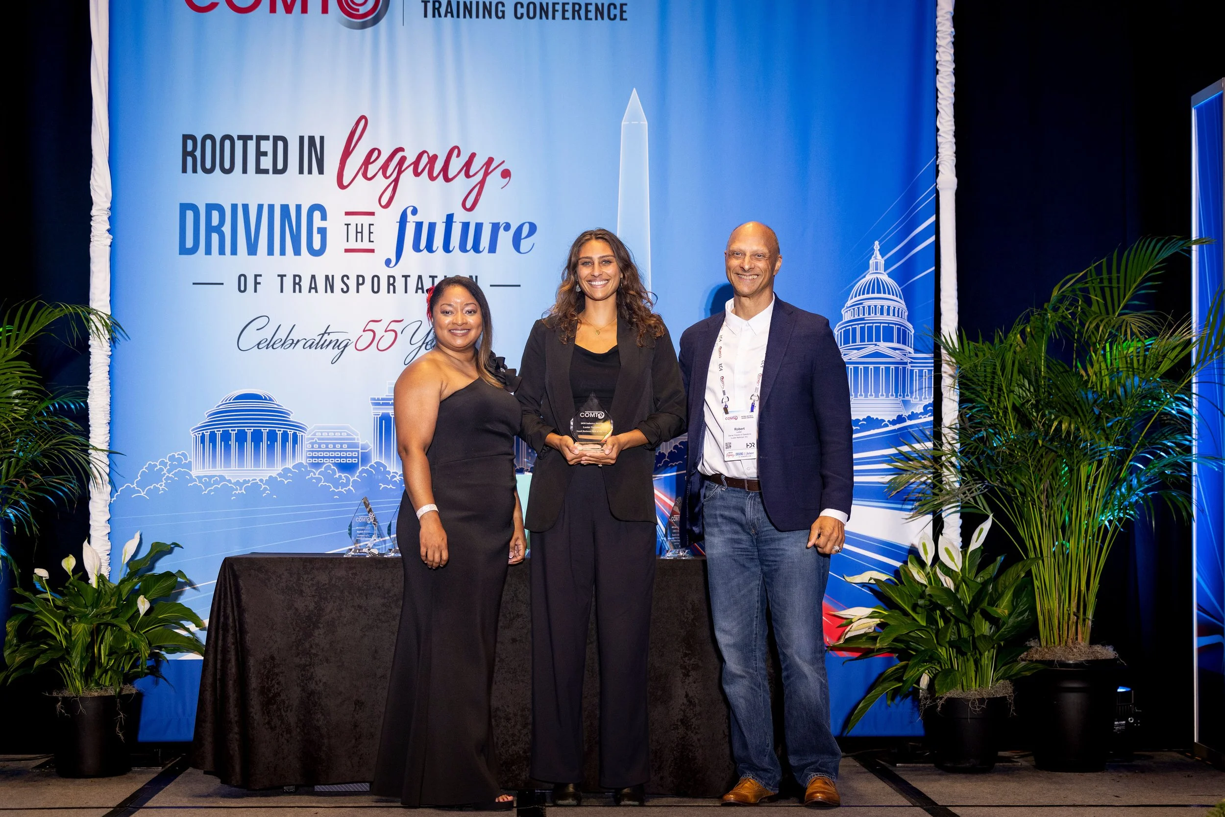 Emily Luster, President of Luster National, accepts the 2026 COMTO Small Business Firm of the Year award alongside Robert Luster and COMTO Deputy CEO Tyra Redus.
