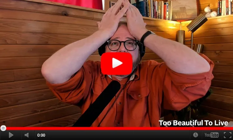 YouTube still image of Andrew holding his hands up to his forehead in apparent anguish