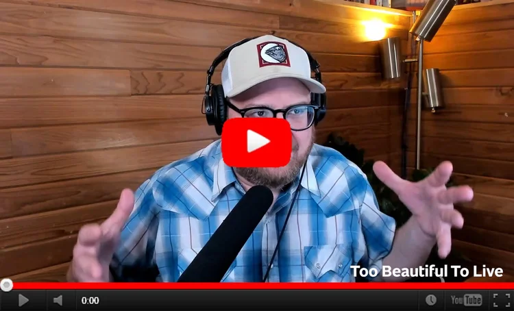 YouTube still image of Andrew in his studio talking into his microphone and gesticulating with his hands