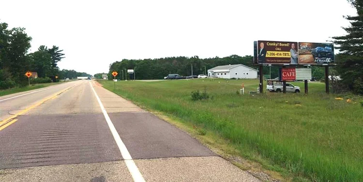 Photo of long roadway in rural Wisconsin that shows a set of billboards along the side of the road. You can just barely make out that one of them looks like it might have Luke and Andrew on it. 