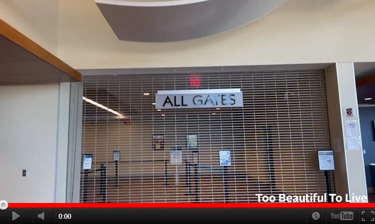 YouTube still image of a closed gate inside an airport that says "ALL GATES" on it