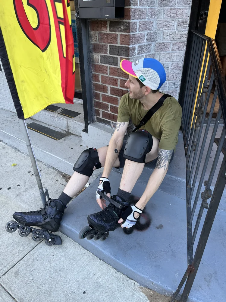 Photo of Listener Jeff sitting on a porch stoop, putting on his rollerblades