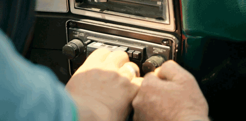 Animated gif of two hands fighting over an old school car radio dial. 