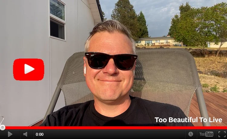 YouTube still image of Luke sitting outside on his deck, smiling into the camera. 