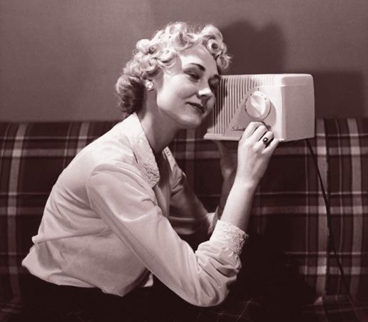 Animated gif of someone twisting a knob back and forth on top of a vintage radio. Looks like the radio is at the beach. We don't see who the hand belongs too. 