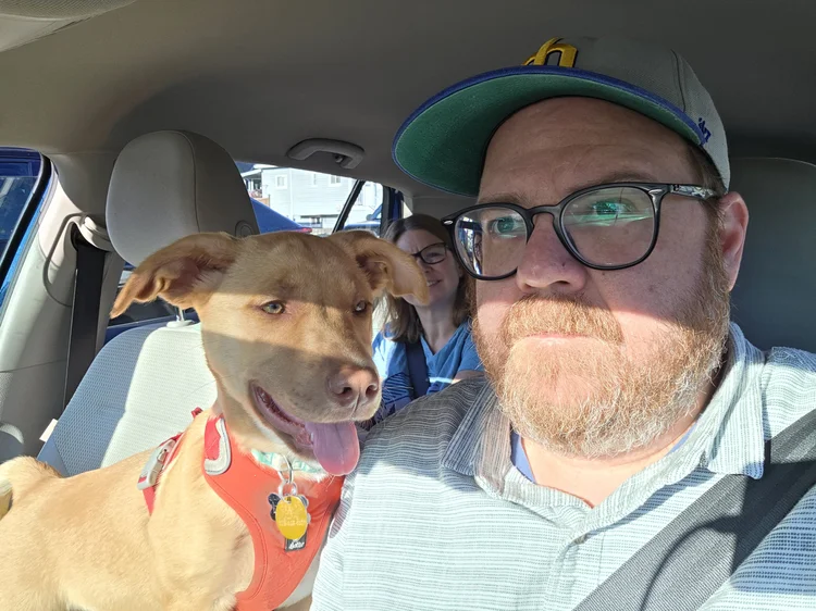 Photo of Lucy, Andrew and Genevieve in the car. Andrew is driving, Lucy in the passenger seat, and Vieves is in the back. 
