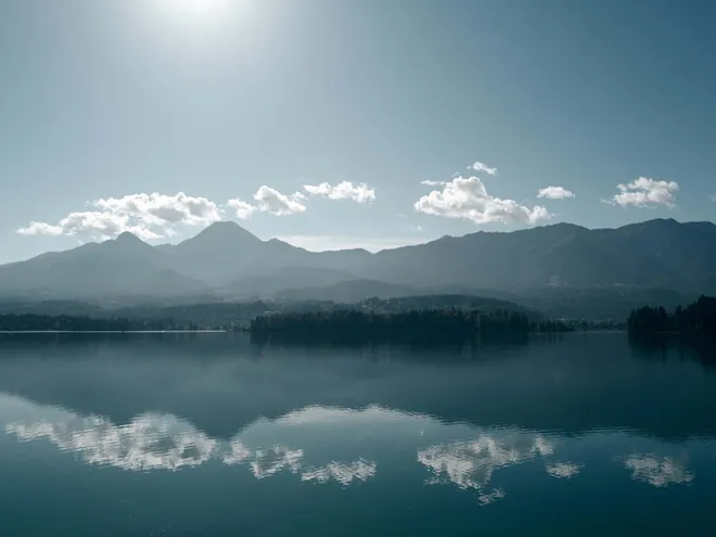 Ruhiger Faaker See spiegelt Wolken und Gipfel