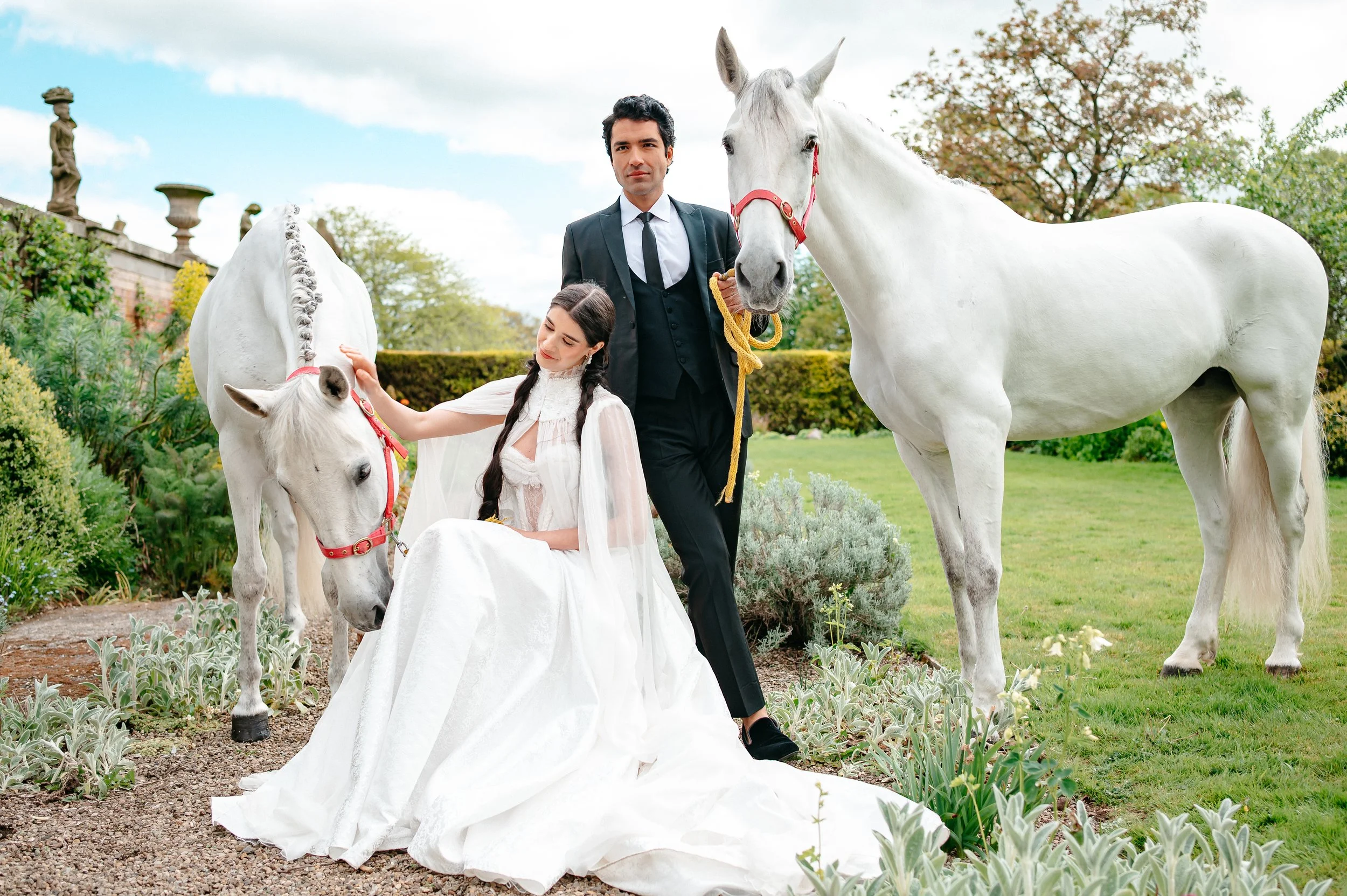 Wedding couple with white horses in a garden