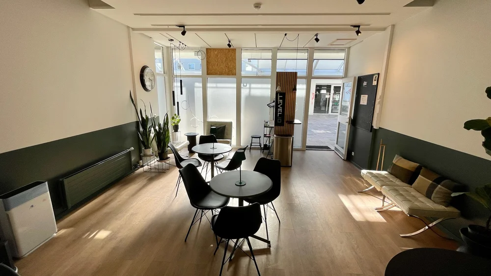 Salurinn moti gluggunum, dagsbirta og bord vid gluggana