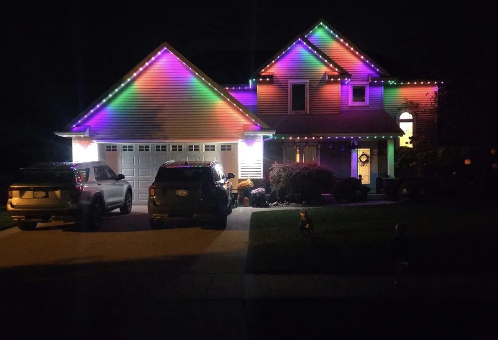 Minleon permanent roofline lighting in colorful patterns on a two-story home at night, installed by Tri-City Lighting