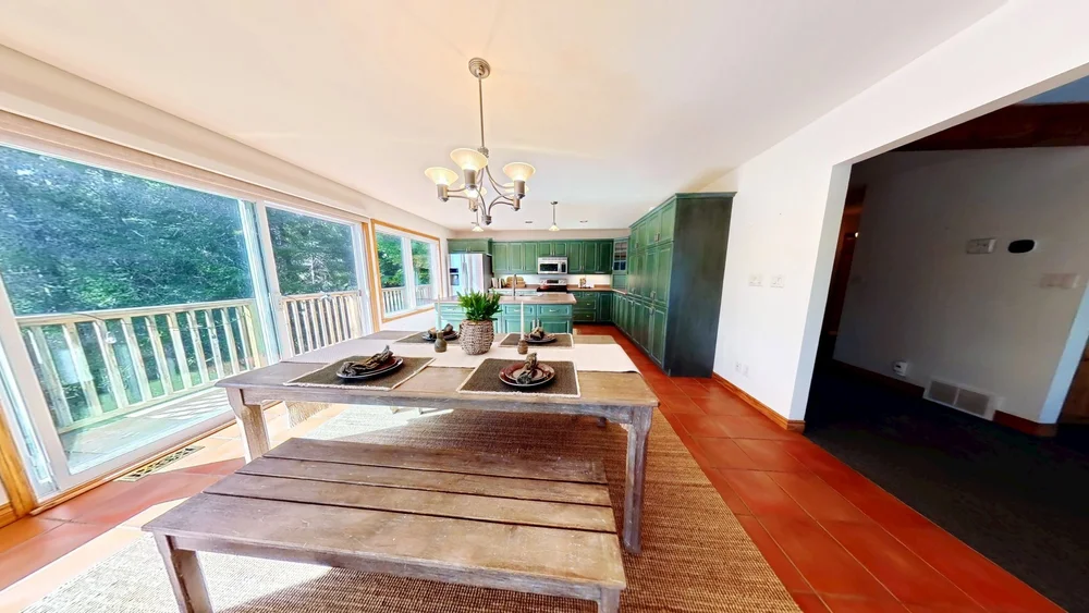 Matterport scan of a dining area beside a green kitchen with deck views
