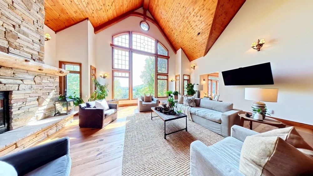 Matterport scan of a vaulted great room with stone fireplace and tall windows