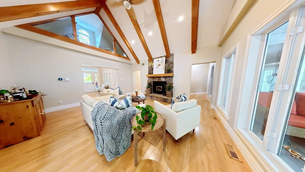Matterport scan of a bright living room with cathedral ceiling and wood beams