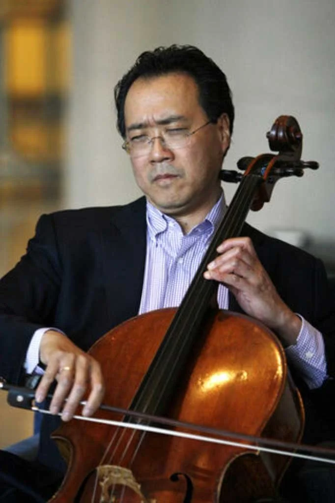 Yo-Yo Ma sitting down and playing the cello.