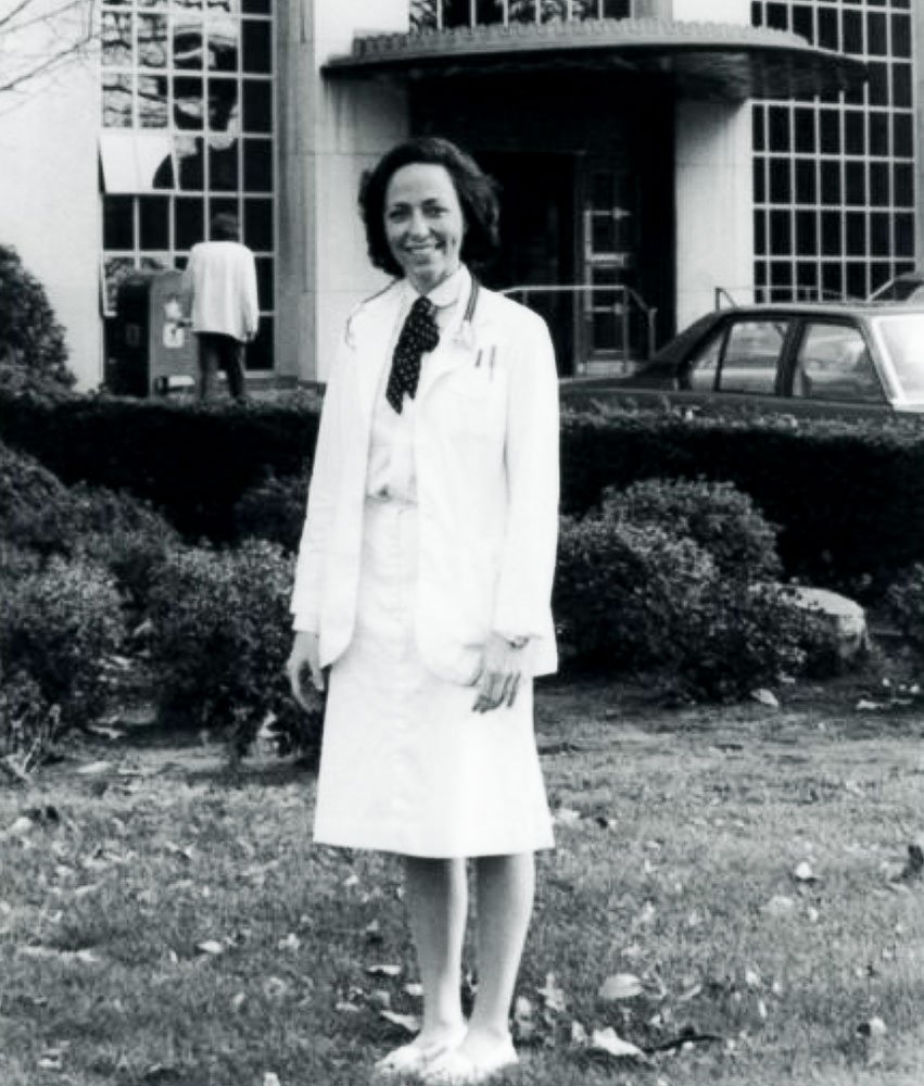 Pamela Cantor stands in front of Cornell Medical School in 1980 wearing a white coat, white skirt, and white shoes denoting that she is a medical student.