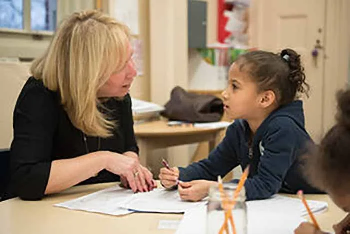 Educator Ronni Gambardella talks to a student at Young Voices Academy of the Bronx at a round table.