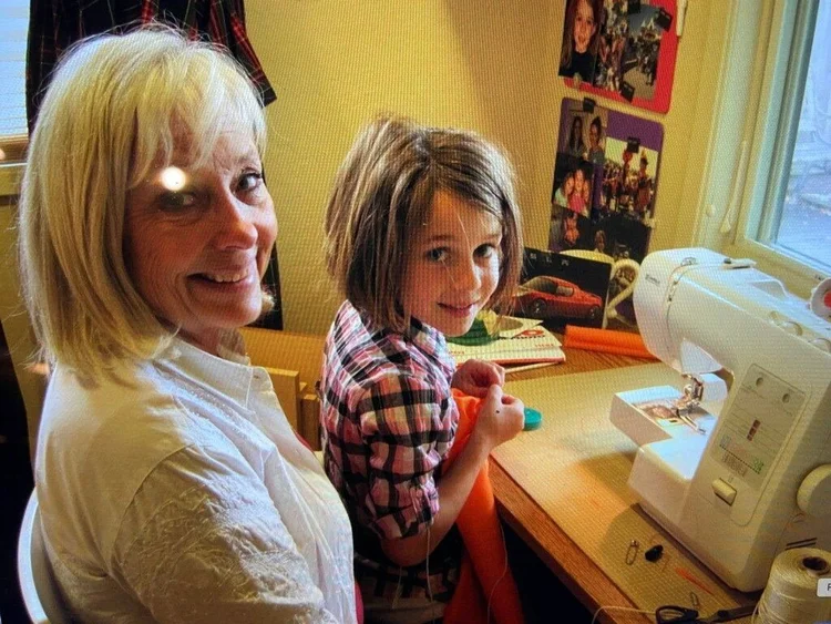 My mother, Marsha Ruth, at the sewing machine with Olivia.