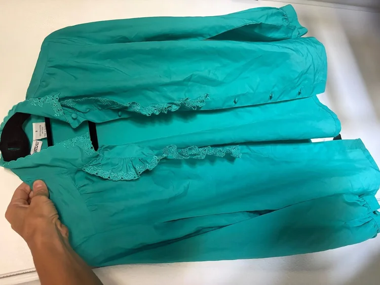 My grandmother’s jade pussy-bow blouse with a ruffled placket, folded.
