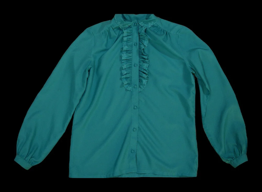 My grandmother’s jade pussy-bow blouse with a ruffled placket, laid flat.