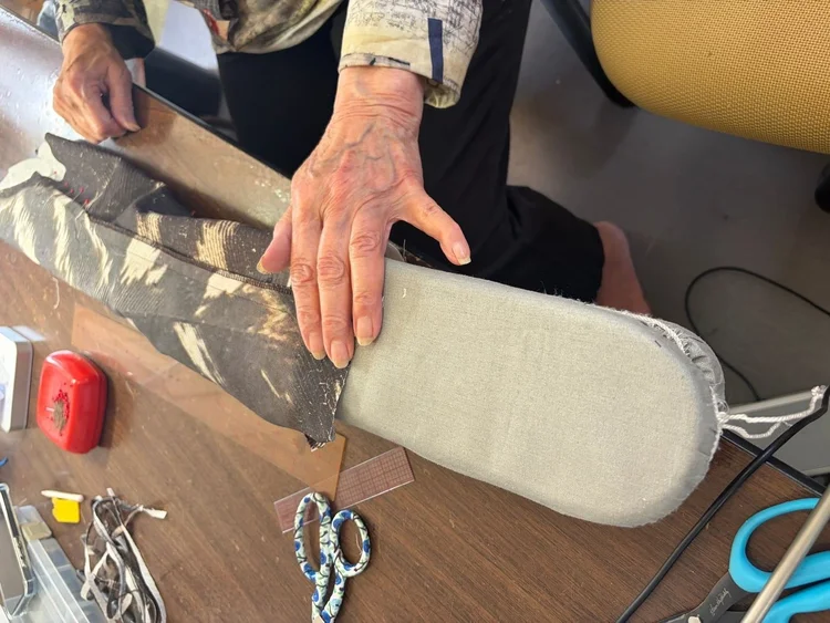 Hands working a seam over a sleeve board.