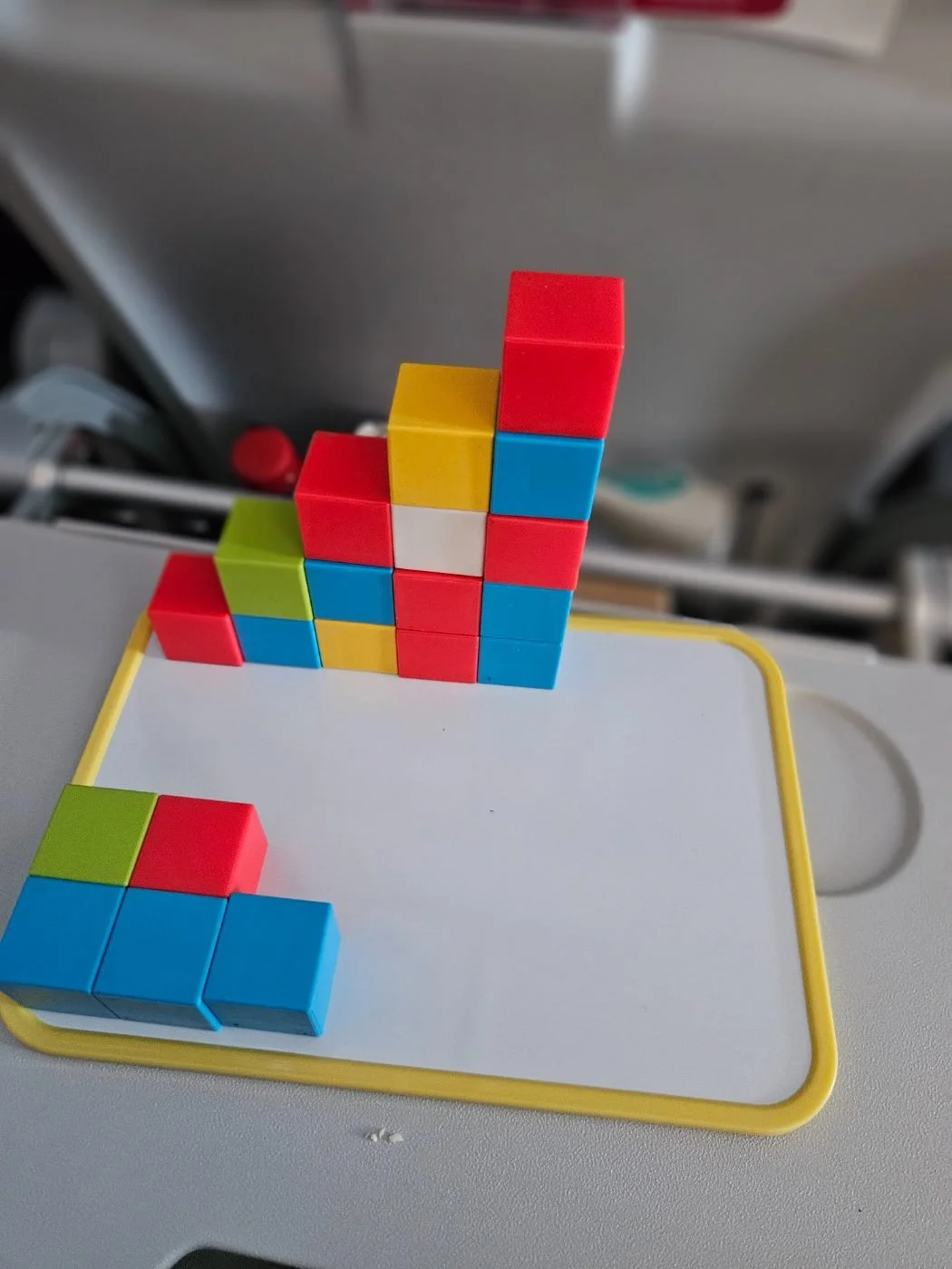 Magnetic cubes stacked into a tower on the whiteboard, on a plane tray table