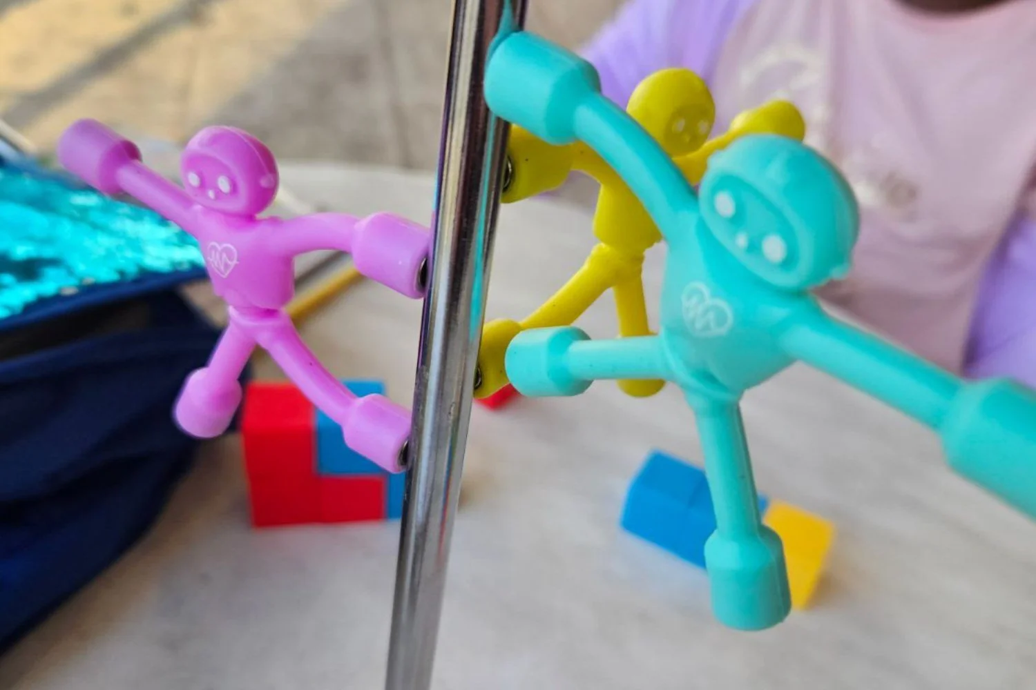 Magnet people from the travel kit stuck to the metal pole of a cafe table