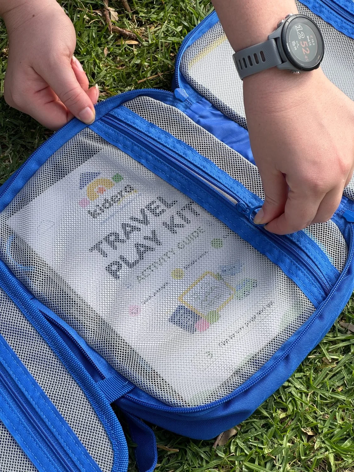 Unzipping the see-through pocket that holds the travel kit's activity guide