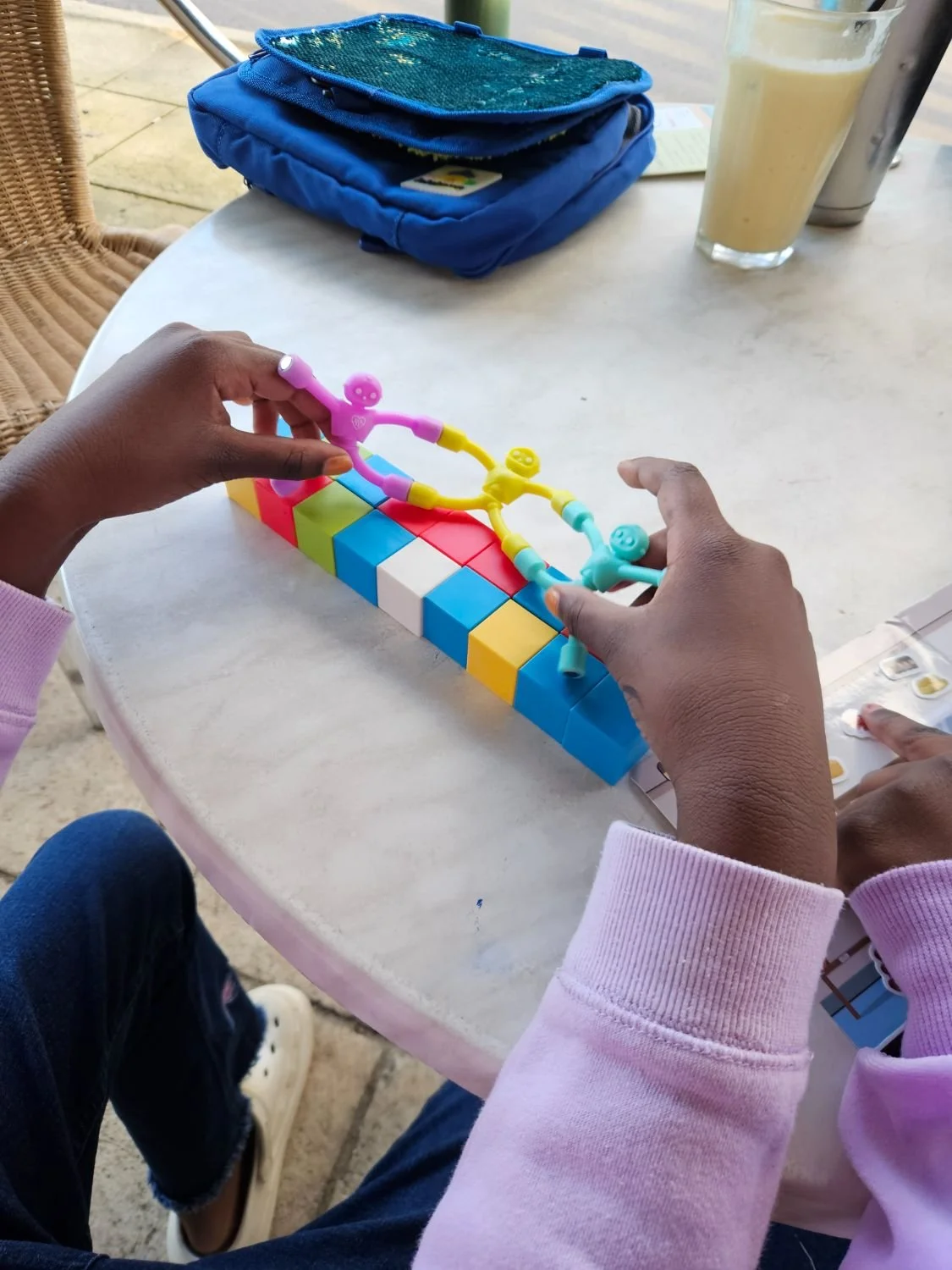 A child building a bridge of magnetic cubes with magnet people on a cafe table
