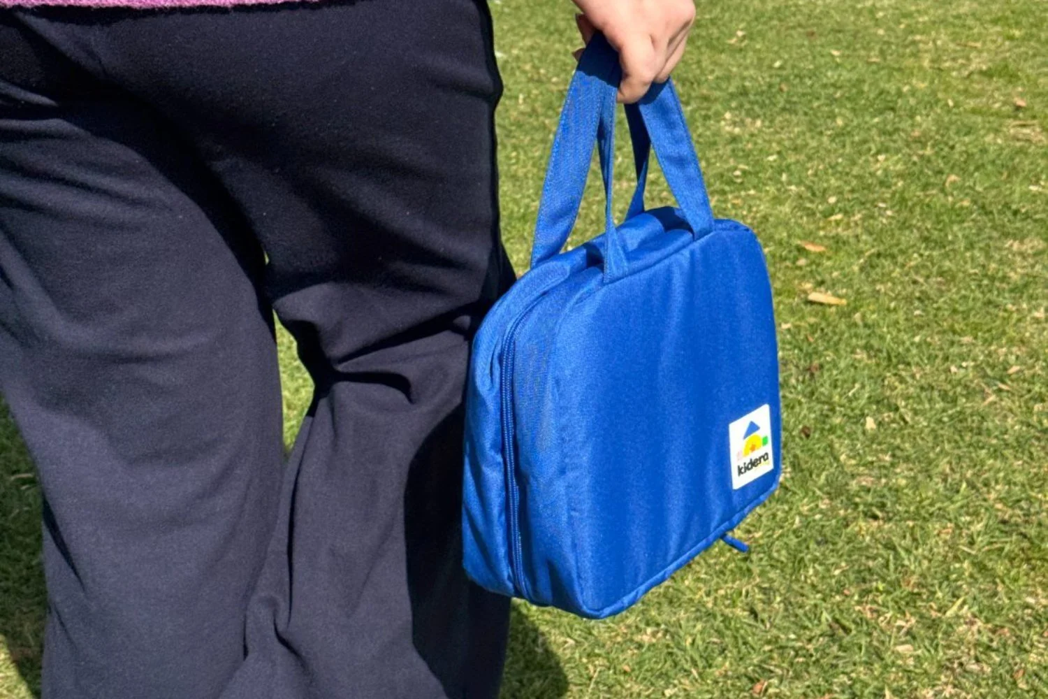 A parent carrying the Kidera Travel Play Kit by its handle