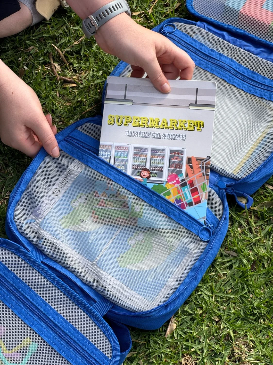 A reusable sticker book sliding out of its zip pocket
