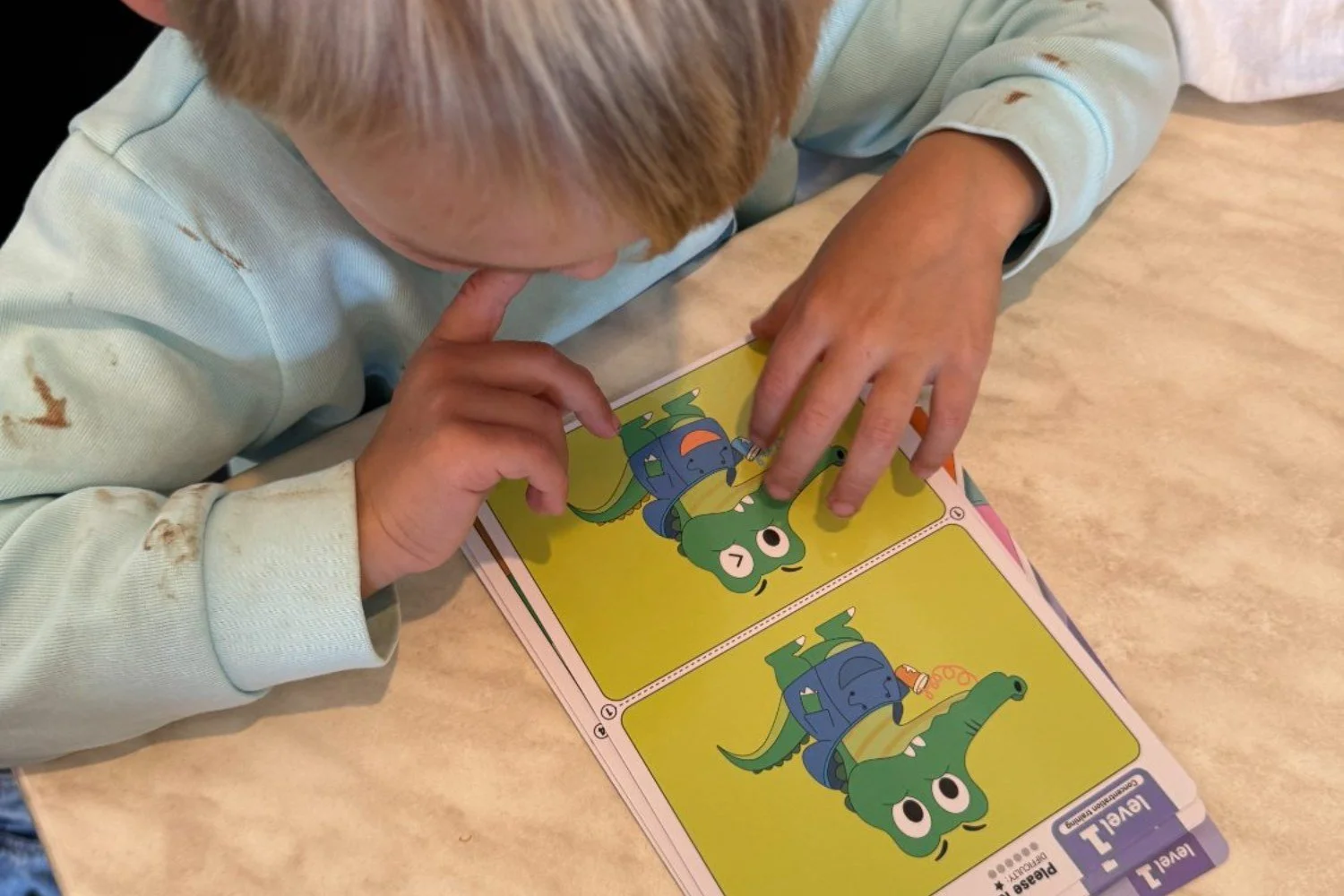 A child leaning in close over a spot-the-difference card from the travel kit