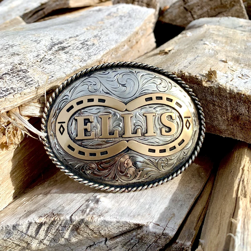 Custom Ellis horseshoe belt buckle on weathered wood