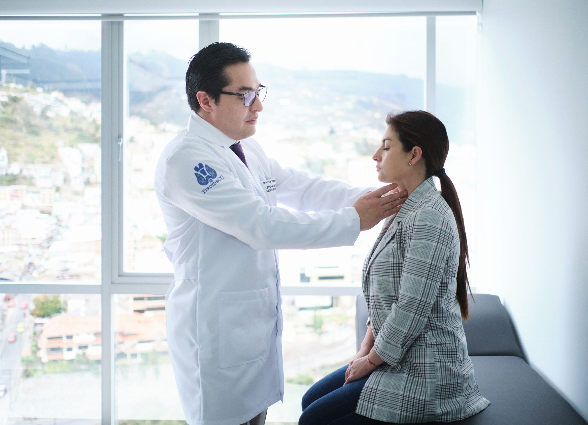 Profesional con bata blanca examinando el cuello de una mujer.
