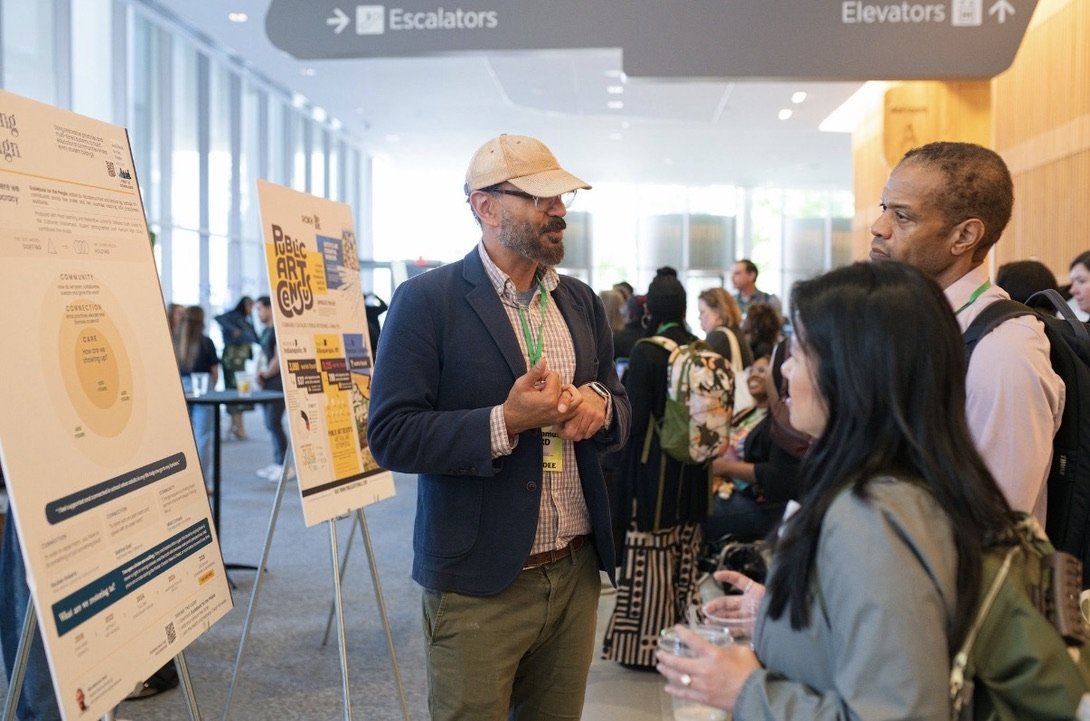 Nicodemus talking with conference attendees beside a research poster