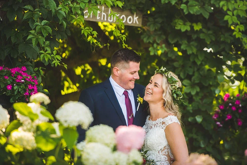 Newlyweds laughing together beneath a leafy arbour at Northbrook Farm near Orillia