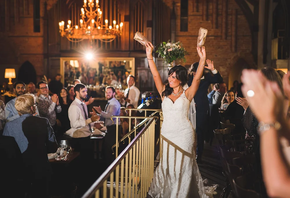 Bride raising her arms as wedding guests cheer during the reception