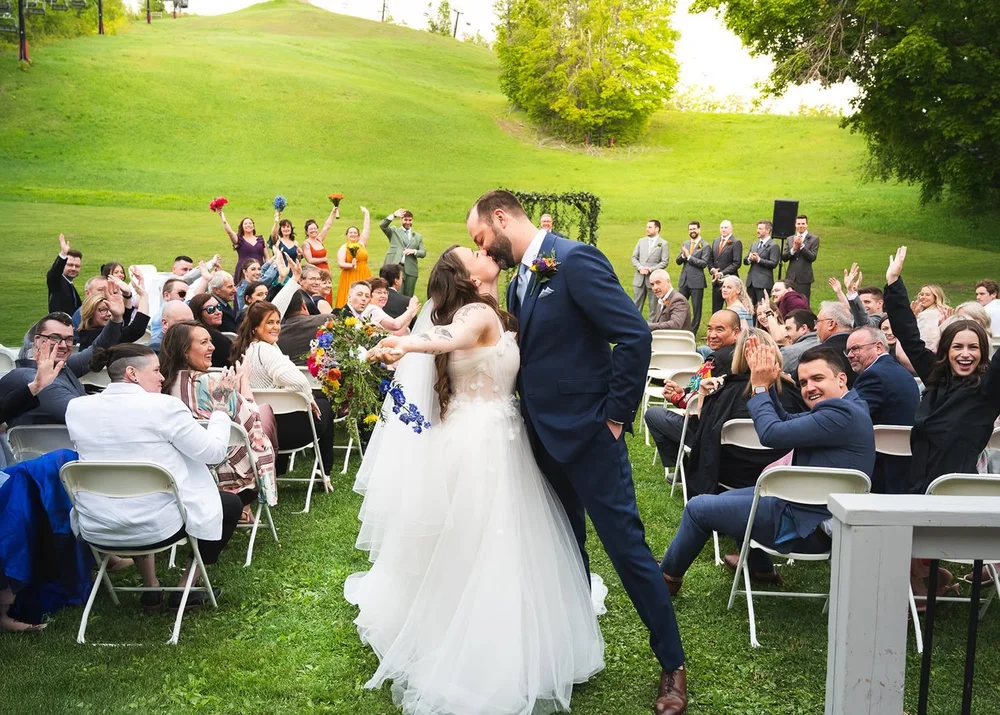 Newlyweds kissing in the aisle as guests cheer at The Heights in Horseshoe Valley