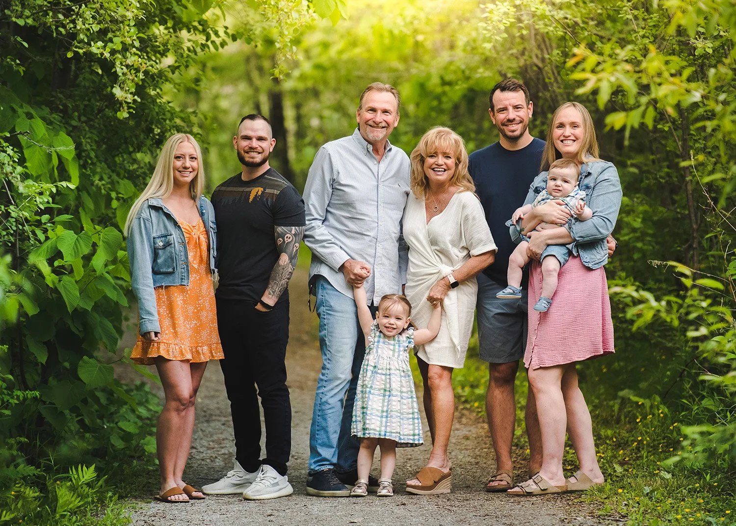 Three generations of a family standing together on a leafy garden path
