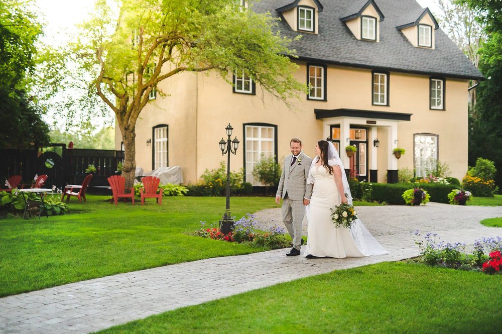 Bride and groom walking past the historic house and gardens at Northbrook Farm
