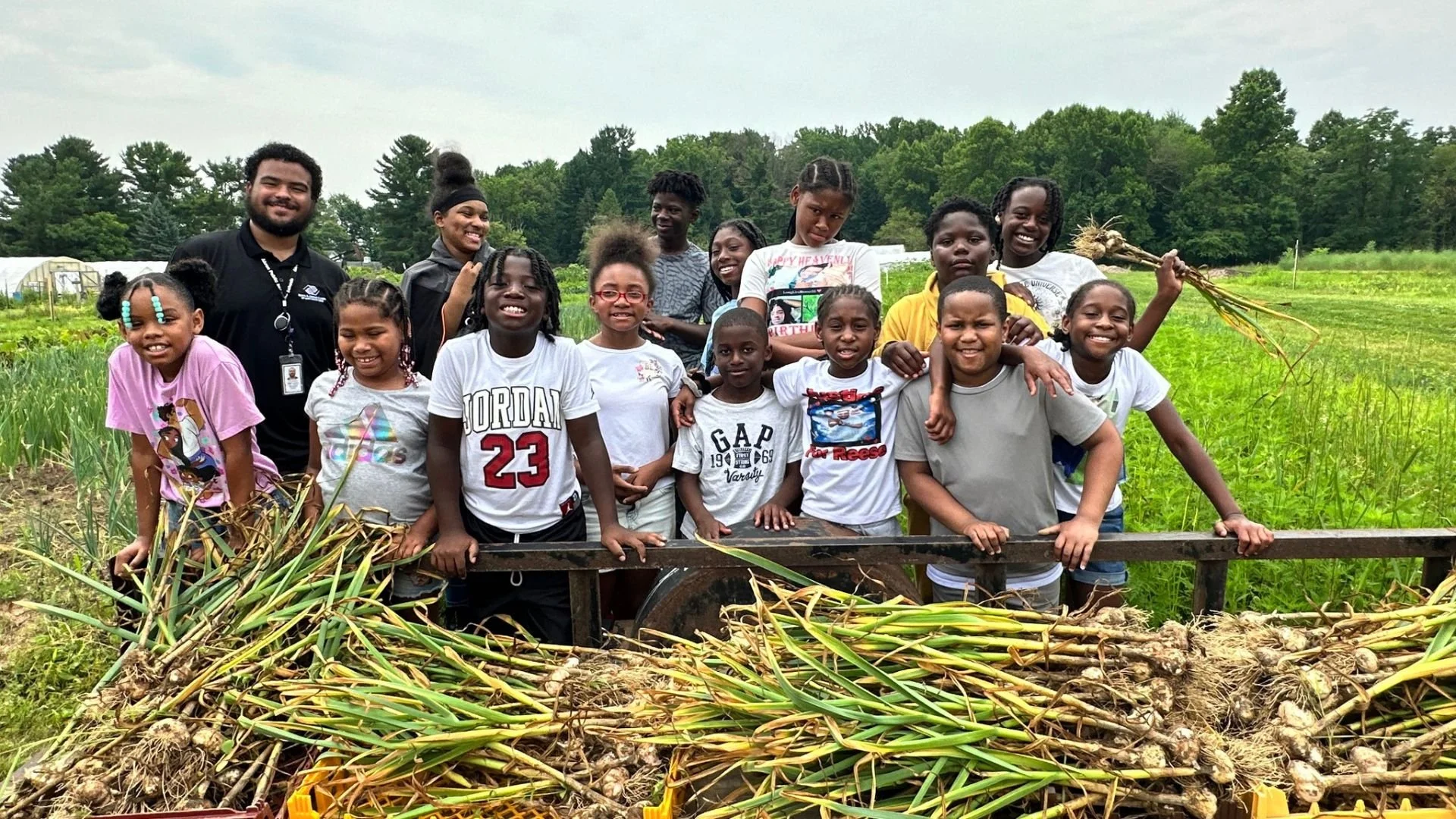 Group of kids pose for picture with harvested garlic