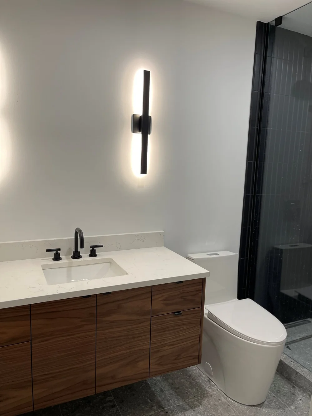 Walnut floating vanity with a quartz top in a Distillery District condo bathroom