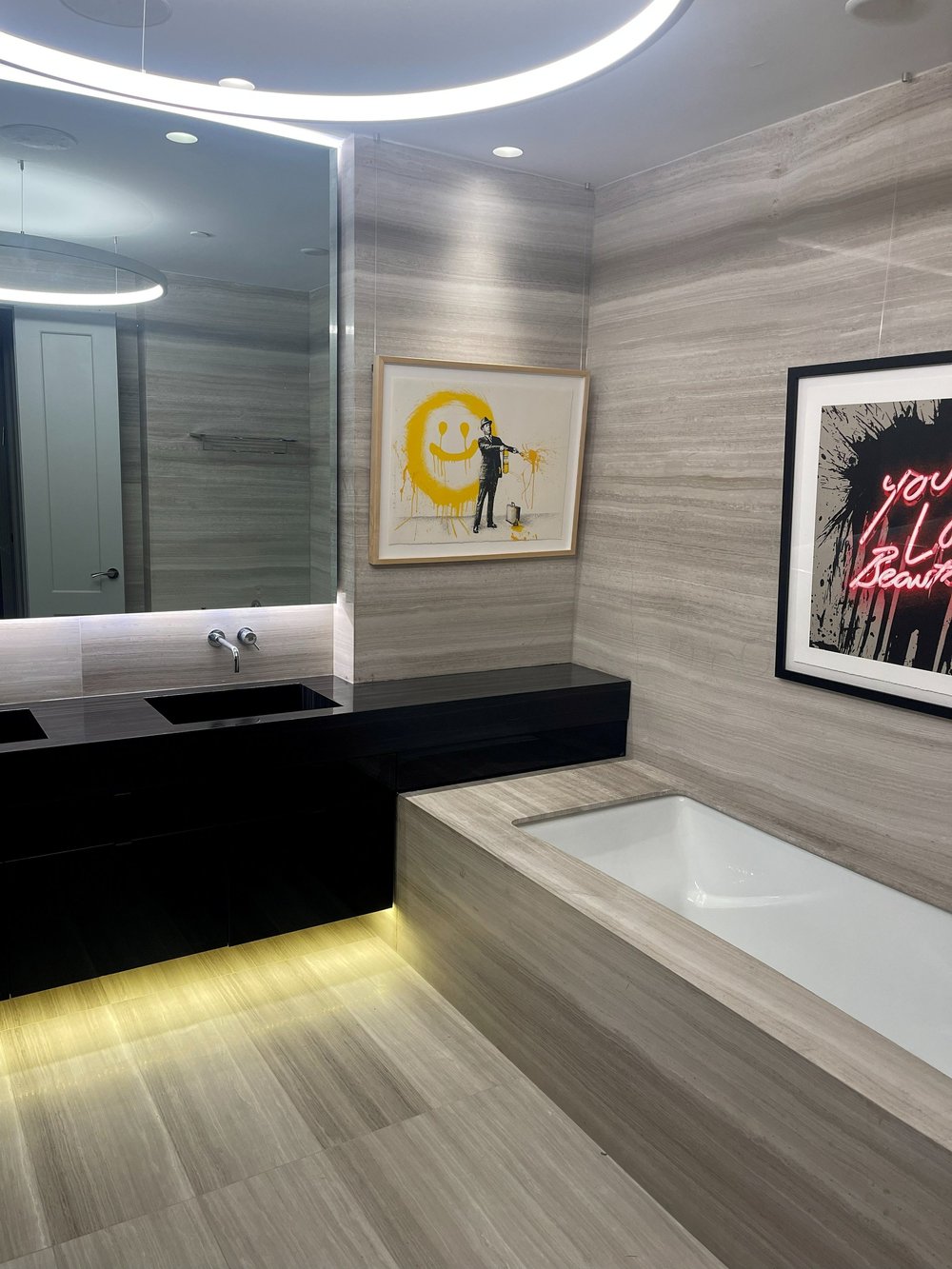 Luxury ensuite with built-in soaker tub, floating black vanity and cove lighting