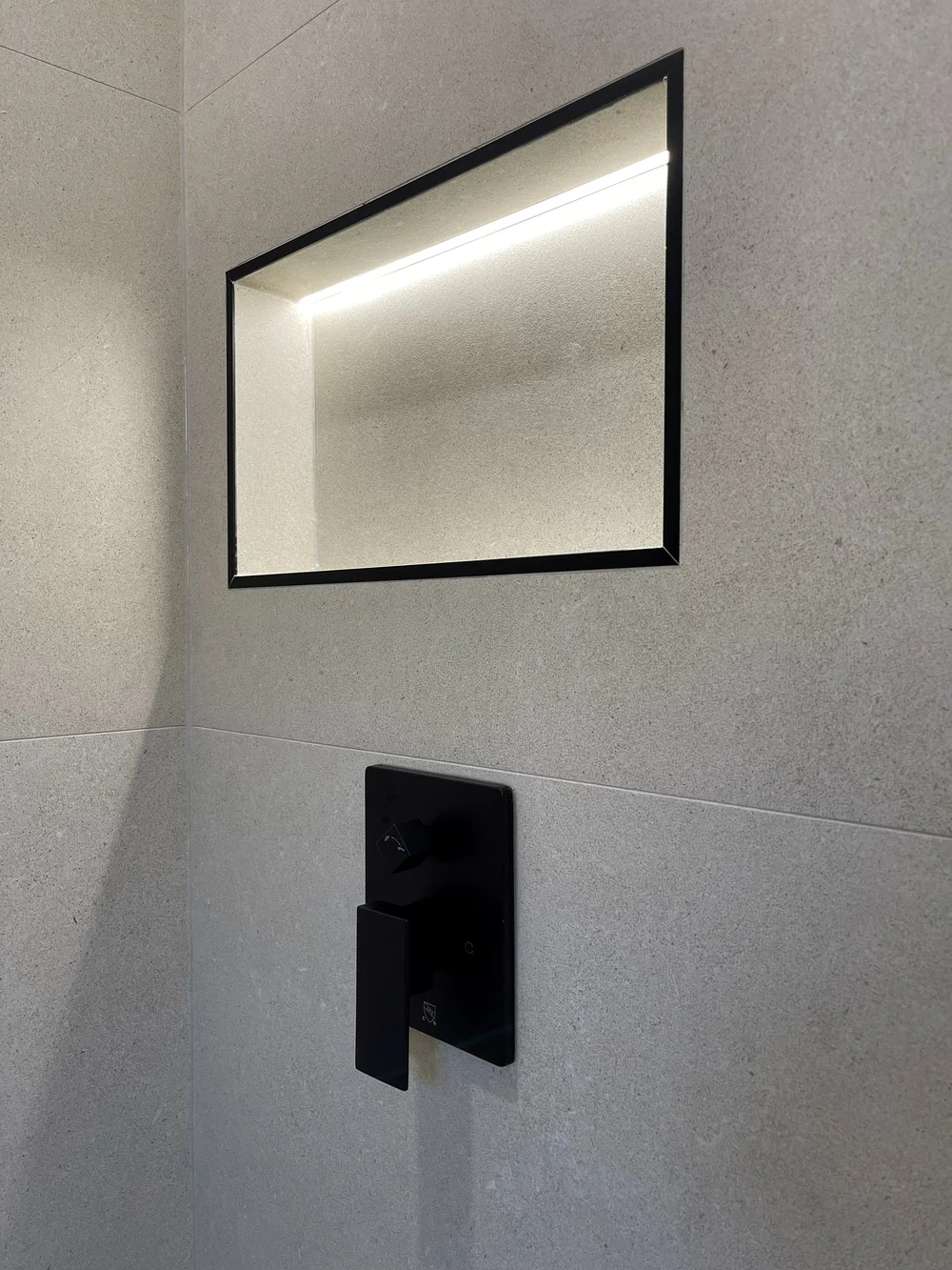Backlit shower niche and matte black controls in a Vaughan curbless shower
